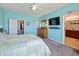 Bright main bedroom features blue walls, ceiling fan, TV, and ensuite bath at 395 Blue Cypress Dr, Groveland, FL 34736