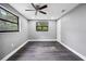 Bedroom featuring wood-look floors, ceiling fan, neutral walls, and two windows at 4123 County Road 124, Wildwood, FL 34785