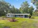 Charming single story home with well-manicured landscaping and gray exterior paint and a blue door at 4123 County Road 124, Wildwood, FL 34785