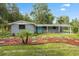Charming home with a blue door and meticulously landscaped front yard featuring colorful plants and mulch at 4123 County Road 124, Wildwood, FL 34785