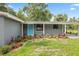 Charming home featuring a blue door, a cozy carport and a landscaped front yard with colorful plants at 4123 County Road 124, Wildwood, FL 34785