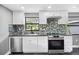 Modern kitchen featuring white cabinets, stainless steel appliances, and a stylish backsplash at 4123 County Road 124, Wildwood, FL 34785