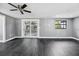 Spacious living room with ceiling fan, gray walls, wood-look flooring, and sliding glass doors to the porch at 4123 County Road 124, Wildwood, FL 34785