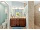 Bright bathroom featuring a double vanity with dark wood cabinets and a tiled walk-in shower at 4987 Belted Kingfisher Dr, Oxford, FL 34484
