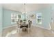 Light-filled dining area with a round table, white chairs, and a modern chandelier at 4987 Belted Kingfisher Dr, Oxford, FL 34484