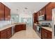 A spacious kitchen with stainless steel appliances, granite countertops, and brown cabinets at 4987 Belted Kingfisher Dr, Oxford, FL 34484