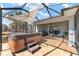 Enclosed lanai featuring a hot tub, tiled flooring, and shaded seating area at 4987 Belted Kingfisher Dr, Oxford, FL 34484