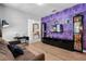 Open living room with purple accent wall, entertainment center and dark wood-style floors at 5241 Oakbourne Ave, Davenport, FL 33837