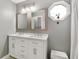Modern bathroom features a white double vanity, framed mirrors, an octagonal window, with a small padded stool at 5380 County Road 122, Wildwood, FL 34785