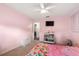 A pink bedroom features a ceiling fan, TV, storage chest and mermaid themed bedding on top of gray carpet at 5380 County Road 122, Wildwood, FL 34785