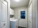 A bright laundry room includes a washer, dryer, storage cabinets, and access door to the exterior at 5380 County Road 122, Wildwood, FL 34785