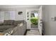 Bright living room featuring gray sofa, neutral walls, dark floors, and open front door at 5380 County Road 122, Wildwood, FL 34785