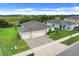 Aerial view of a charming home featuring a three-car garage, manicured lawn, and delightful landscaping at 641 Black Eagle Dr, Groveland, FL 34736