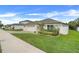 A single-story home showcasing a three-car garage, manicured lawn, and vibrant landscaping under a clear, sunny sky at 641 Black Eagle Dr, Groveland, FL 34736