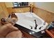 Close up of the jacuzzi bathtub featuring brown fixtures, black countertops, and travertine backsplash at 707 S Dixie Dr, Howey In The Hills, FL 34737