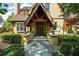 Inviting front entrance with a peaked portico, double wooden doors, and stone walkway, surrounded by lush greenery at 707 S Dixie Dr, Howey In The Hills, FL 34737