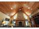 Spacious living room featuring a vaulted ceiling, stone fireplace, hardwood floors, and custom built-in shelving at 707 S Dixie Dr, Howey In The Hills, FL 34737