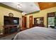 Spacious main bedroom featuring wooden floors, a large TV, and an antique dresser with a mirror at 707 S Dixie Dr, Howey In The Hills, FL 34737