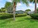 Beautifully landscaped home with carport and lush green lawn and mature trees at 727 Turnberry Ln, The Villages, FL 32159