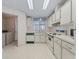 An open kitchen includes white cabinetry, countertops, and appliances, with a view of the laundry room. Plenty of storage space at 727 Turnberry Ln, The Villages, FL 32159