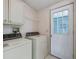 Functional laundry room with white appliances, storage cabinets and easy outdoor access through an adjacent glass paneled door at 727 Turnberry Ln, The Villages, FL 32159