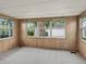 Bright sun room with wood paneled walls, neutral carpet, and large windows at 727 Turnberry Ln, The Villages, FL 32159
