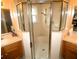 Bathroom with double sinks, wood cabinets, tile floors, and an enclosed shower with glass door at 751 Old Oaks Ln, Leesburg, FL 34748