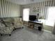 Sitting room with two sitting chairs, television, and striped accent wall with baseboard mural at 751 Old Oaks Ln, Leesburg, FL 34748
