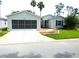 Single-story home with gray siding, screened garage door, and front patio with red chairs at 751 Old Oaks Ln, Leesburg, FL 34748