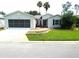 Charming single-story home with well-manicured lawn, gray siding and a screened garage door at 751 Old Oaks Ln, Leesburg, FL 34748