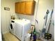 Bright laundry room with washer, dryer, cabinet storage, and tiled flooring at 751 Old Oaks Ln, Leesburg, FL 34748