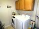 Well-lit laundry room with washer, dryer, cabinet storage, and tiled flooring at 751 Old Oaks Ln, Leesburg, FL 34748