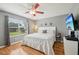 Bedroom with wood floors, ceiling fan, and a large window letting in natural light at 8039 Se 174Th Belhaven Loop, The Villages, FL 32162