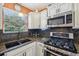 Kitchen with stainless steel gas range, microwave, granite counters, and a black composite sink at 8039 Se 174Th Belhaven Loop, The Villages, FL 32162