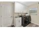 Laundry room with modern washer and dryer, white cabinets, and convenient sink area for efficient chores at 832 Parrish Pl, The Villages, FL 32163
