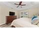 Comfortable main bedroom featuring a ceiling fan, a dresser with a TV, and a window with plantation shutters at 832 Parrish Pl, The Villages, FL 32163