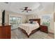Serene main bedroom features a tray ceiling, sliding glass doors to a patio, and a comfortable bed with stylish bedding at 832 Parrish Pl, The Villages, FL 32163