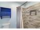 Well-lit bathroom with a blue accent wall, decorative shower tile and modern fixtures at 8639 Se 141St Pl, Summerfield, FL 34491