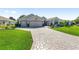 Charming single-story home featuring a three-car garage, beautiful landscaping, and a paved driveway at 9059 Se 177Th Grassmere St, The Villages, FL 32162