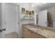 Well-lit bathroom featuring a vanity, mirror, and decorative shelves with a view to the kitchen at 9321 Se 172Nd Augusta Ln, The Villages, FL 32162