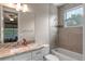 Bathroom with granite countertops, vanity mirror, ceramic tiled shower walls, and natural lighting at 9512 Mid Summer Ln, Leesburg, FL 34788