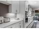 Kitchen featuring white cabinetry, stainless steel appliances, a gray tile backsplash and marble countertops at 9512 Mid Summer Ln, Leesburg, FL 34788