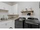 A modern laundry room featuring front loading washer and dryer, white cabinets, and ample counter space at 9512 Mid Summer Ln, Leesburg, FL 34788
