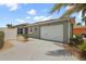 Exterior view of the home featuring a two-car garage, desert landscaping, and concrete driveway at 997 Oscar Ln, The Villages, FL 32162