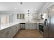 Modern kitchen boasts stainless steel appliances, ample gray cabinetry, stone countertops, and stylish fixtures at 997 Oscar Ln, The Villages, FL 32162