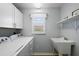 Well-lit laundry room with washer, dryer, utility sink, ample cabinet and shelf storage space at 997 Oscar Ln, The Villages, FL 32162