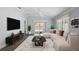 Stylishly furnished living room with a plush white sofa, patterned rug, and modern entertainment center at 997 Oscar Ln, The Villages, FL 32162