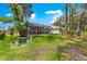 Spacious backyard with screen enclosed patio and beautiful lawn and landscaping under shady trees at 1010 Sierra Blanca Ct, Lady Lake, FL 32159