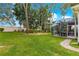 View of backyard with screen enclosed patio with beautiful lawn and landscaping under shady trees at 1010 Sierra Blanca Ct, Lady Lake, FL 32159