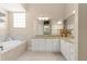 Bright bathroom features a soaking tub with tile surround and granite counters with white cabinets at 1010 Sierra Blanca Ct, Lady Lake, FL 32159